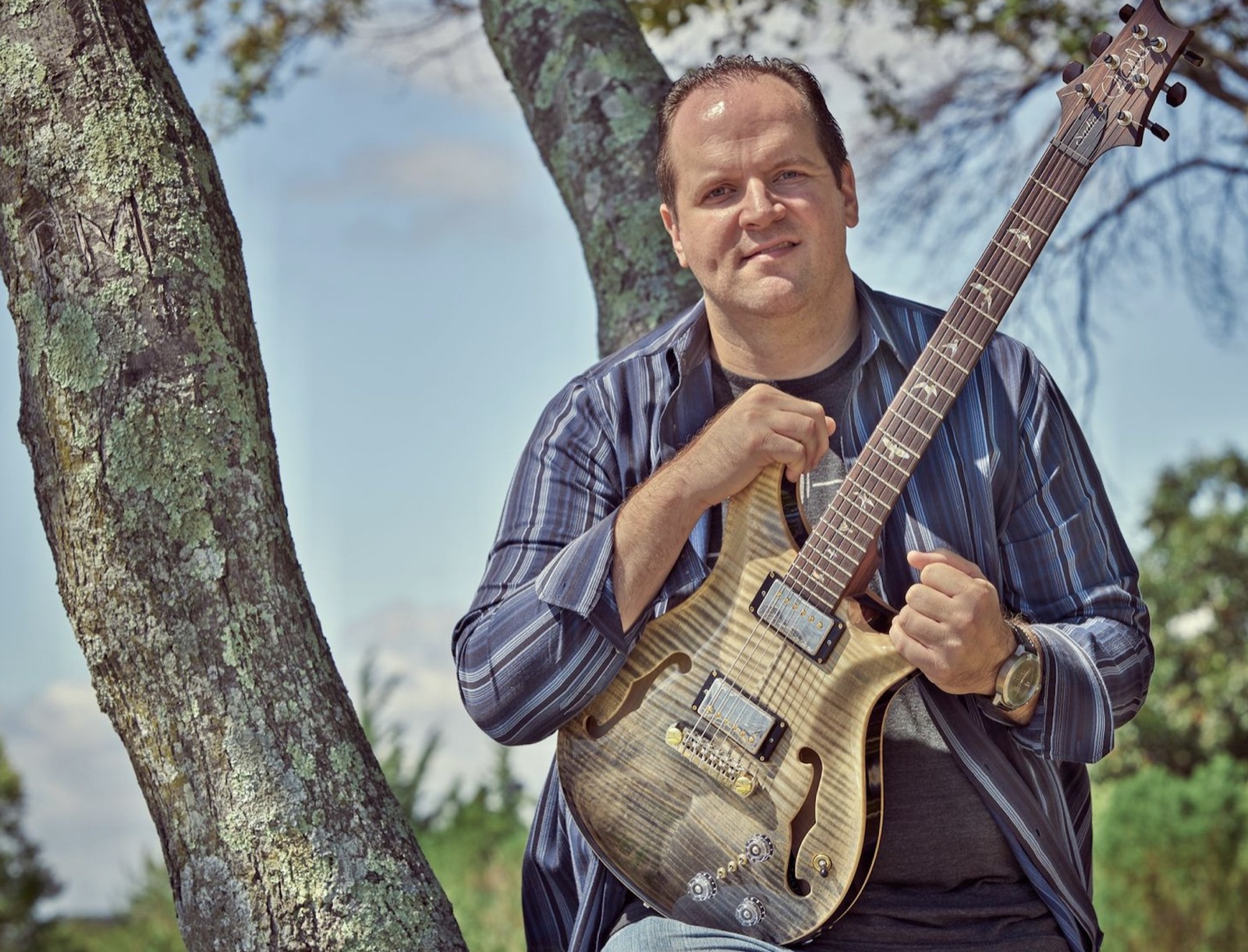 Ron Gilmartin holding his guitar outdoors